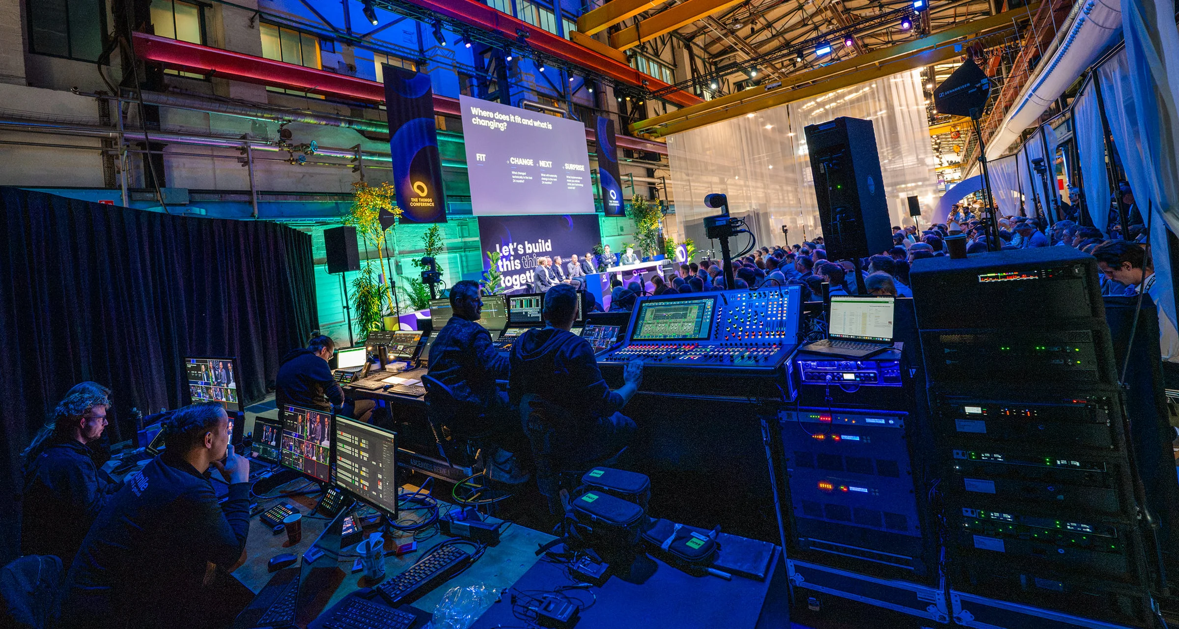 The production crew at their desks behind the audience in the Theater at The Things Conference 2026, with a panel on stage in the distance.